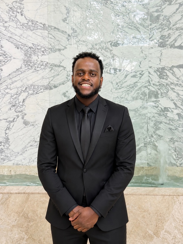 DJ Benjii wearing a black suit and tie